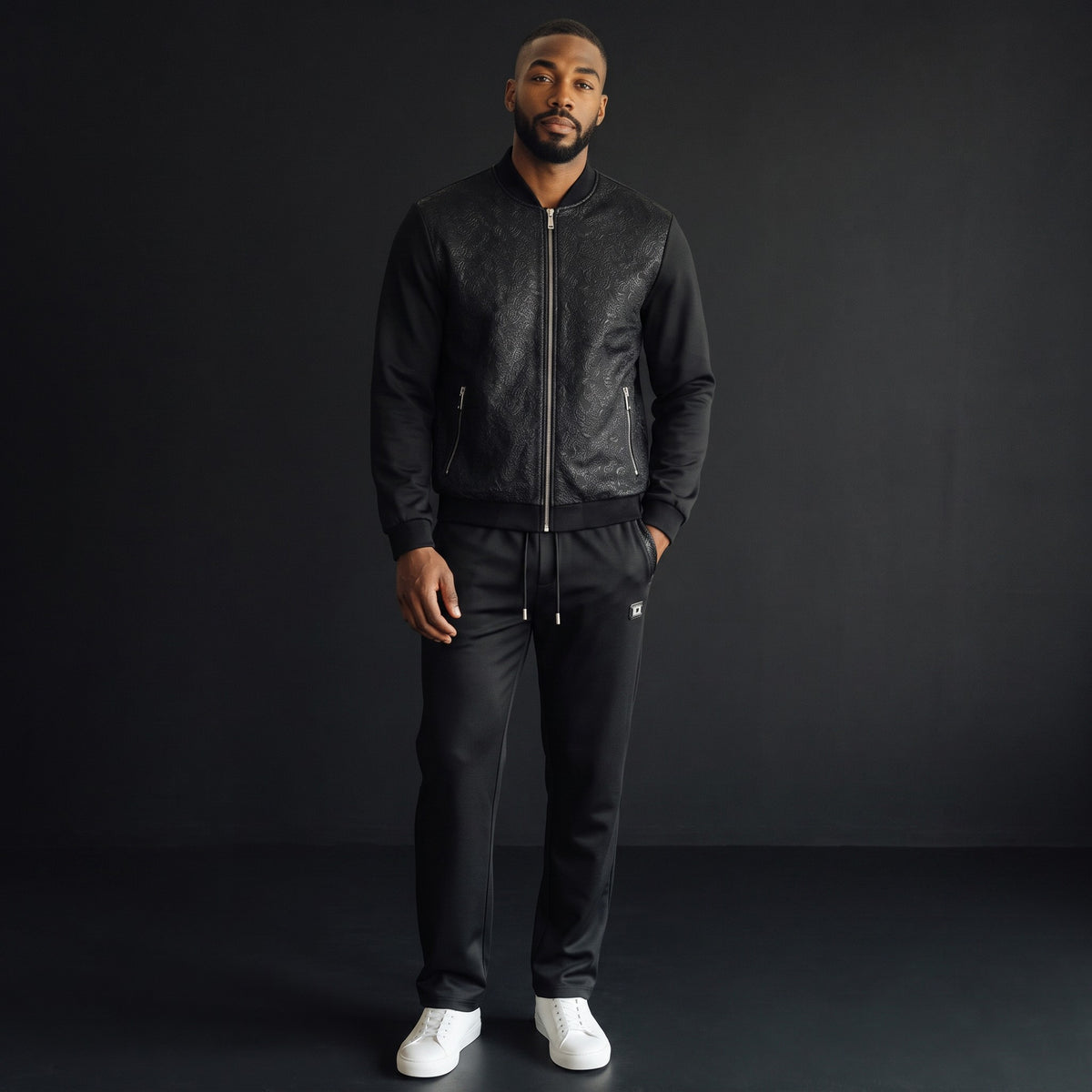 Model wearing The City Warehouse-Menswear black Barocco Regalia embossed floral tracksuit with white sneakers
