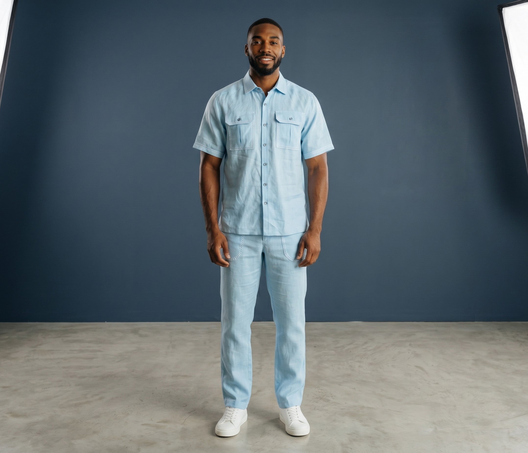 A man wearing a light blue short-sleeve lace shirt and matching trousers from The City Warehouse-Menswear.